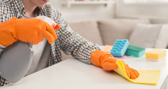 Unrecognizable man cleaning home with detergents