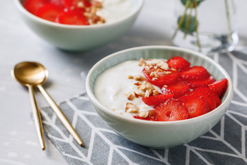Close-up of bowls with coconut yoghurt, fresh strawberries and almonds. The concept of breakfast and a healthy lifestyle. Scandinavian style.