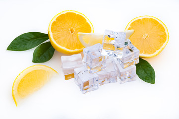 Cubes of cold ice, slices and halves of a fresh, bright lemon with green leaves on a white background.