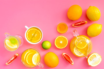 Brew fruit tea. Teacup and teapot near orange, lime, lemon, grapefruit on pink background top view space for text
