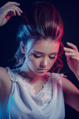 Fashion portrait of young elegant girl in white dress. Black background, studio shot.