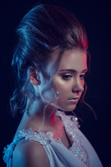 Fashion portrait of young elegant girl in white dress. Black background, studio shot.