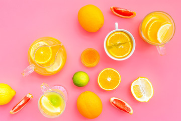 Brew fruit tea. Teacup and teapot near orange, lime, lemon, grapefruit on pink background top view space for text