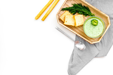 Green broccoli cream soup with broccoli served with rusks and greens on white background top view space for text