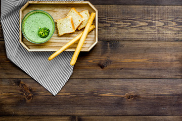 Natural, organic food. Green vegetable soup-puree in bowl ready to eat served with rusks on dark wooden table top view space for text