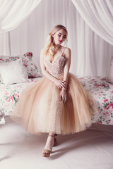 fashion studio photo of beautiful young girl with brown hair wearing luxurious beige dress,