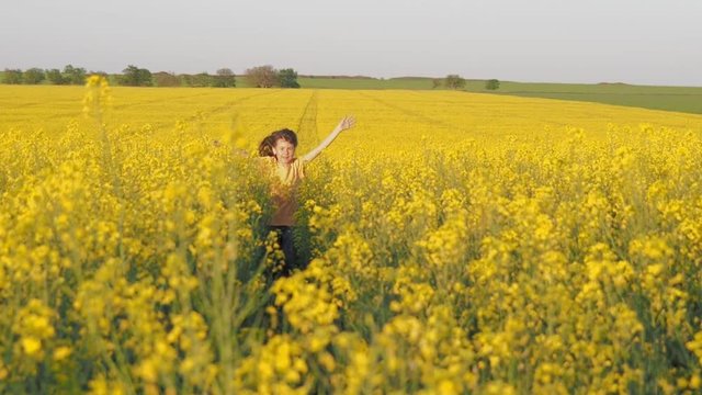 Child in the rapeseed field. Little girl on a field of yellow flowers. A happy child is running in the field. The child is in flowers.