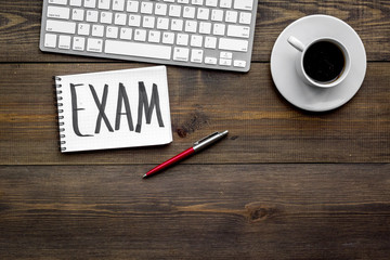 Preparing for the exam. Word Exam written in notebook on student's desk with computer on dark wooden backgrond top view space for text