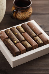 Handmade bonbons with gold splashes in box on wooden background