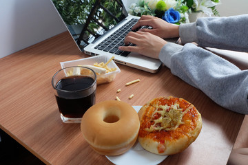Eat snacks with Donut bread, Pizza and cola water drink during work with laptop computer.
