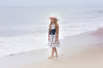 Sweet girl in a hat walking along the seashore