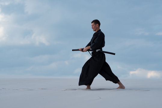 Man is practicing Japanese martial arts in the desert