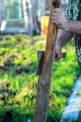 A man cuts wood with an ax in the garden .