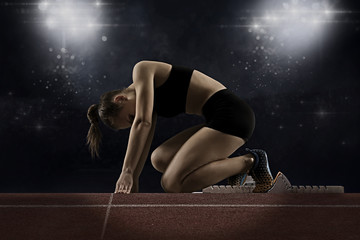 Woman sprinter leaving starting blocks on the athletic track