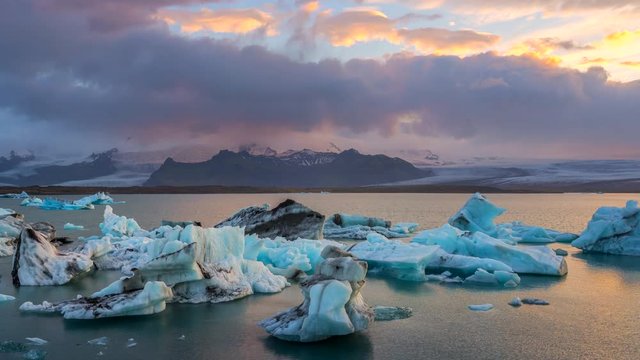 Glaciers in Jökulsárlón glacial lagoon water, near Vatnajkull National Park in southeastern Iceland at sunset. Zoom out. 4K UHD timelapse.