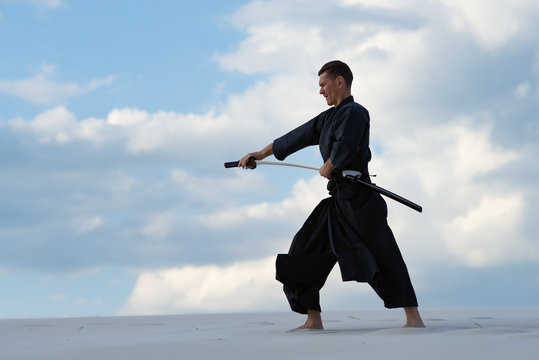Focused man practicing Japanese martial art in desert