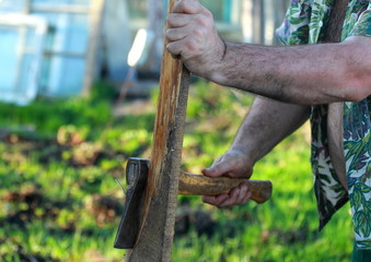 A man working in the garden. He cuts wood.