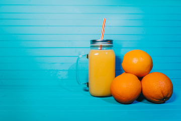 Freshly squeezed orange juice with fruits on a turquoise background, copy space