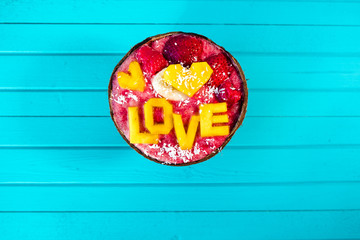 Smoothies bowl with fruit and inscription love of mango on turquoise wood background, copy space