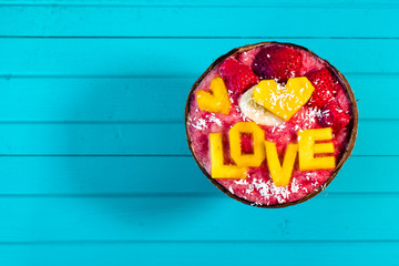 Smoothies bowl with fruit and inscription love of mango on turquoise wood background, copy space. Top view