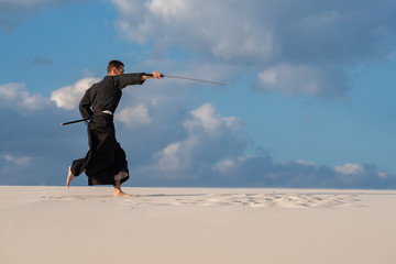 Man practicing Japanese martial art in desert