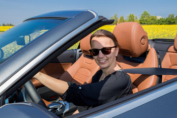 Naklejka premium Attractive smiling Brunette Young Woman in a luxury convertible car.