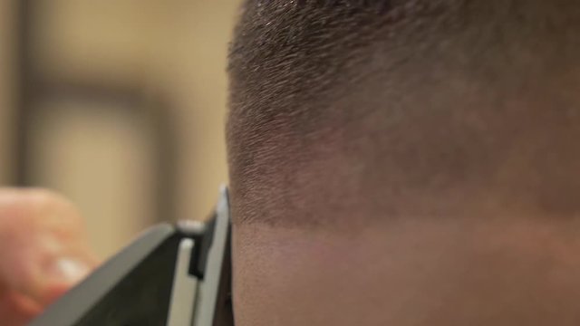 Barber uses buzzer on hair, close up