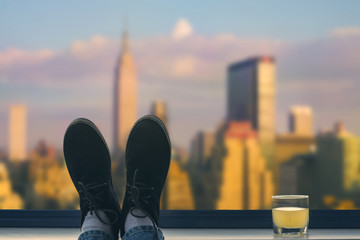 A male feet in the shoes on the balcony on the background Manhattan. New York City