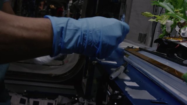 Close up, astronaut writes on tin foil in International Space Station