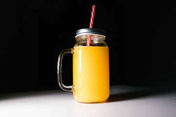 Orange juice in a glass jar on a black background