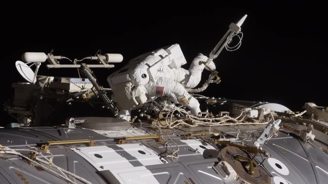 Astronaut working on exterior of International Space Station, low angle