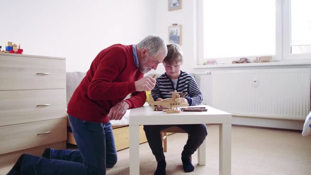 Senior grandfather with a small grandson at home drawing.