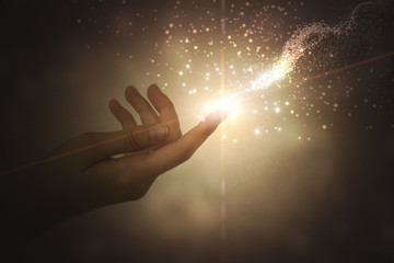 A hand giving the flow of energy. Magic, fantasy. Glowing particles - obrazy, fototapety, plakaty