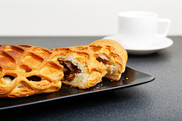 Closeup homemade strudel with apples, raisin and cinnamon on dark table. Shallow focus.