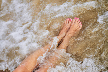 Woman barefoot on the summer beach. close up of a young woman the beach. Travel Concept.Texture background.