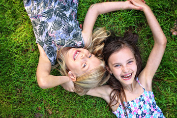 joyful friends lie on the grass and laugh