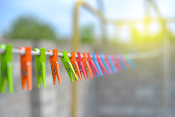 Color clothespins hang on the clothesline. laundry hook, colorful, pegs, rope ,outside, sun ,green, summer decorations, village, blue, sky , yellow ,red ,pins ,pink ,over