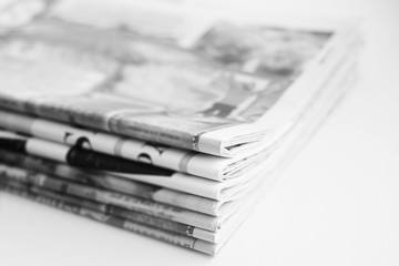 Pile of fresh morning newspapers on the table at office. Latest financial and business news in...