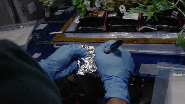 Close up, astronaut writes on tin foil in International Space Station