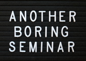 The words Another Boring Seminar in white plastic letters on a black letter board as a humorous reminder to provide content of interest to your audience