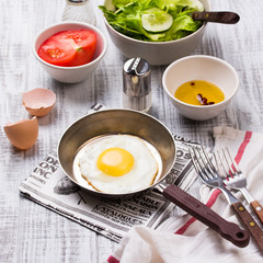Fried eggs in a frying pan with tomatoes and vegetable salad for breakfast
