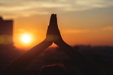 hands of woman in the yoga pose on the sunset and town background