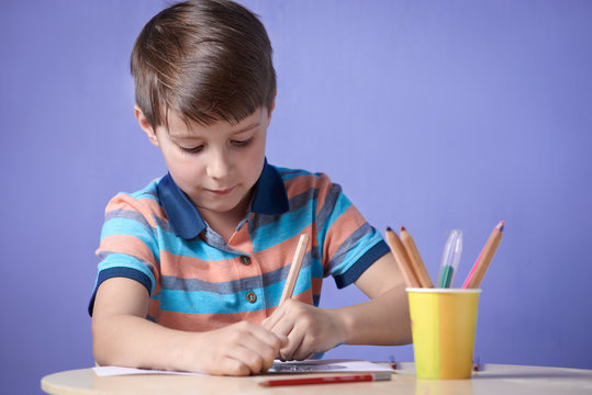 Caucasian boy drawing with colorful pencils.