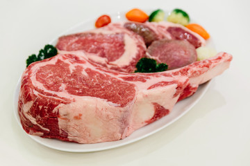 Different types of raw beef with fresh herbs and vegetables on the table for customer selection.