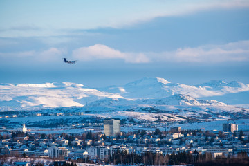 The plane is landing in a Reykjavik downtown in a golden evening light. Capital city of Iceland...