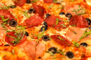 Homemade salami pizza with ham and olives. Close-up view of fresh pizza.