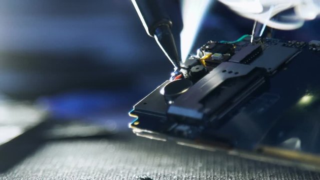 service repair shop. mobile phone maintenance and renovation. hands soldering wires on disassembled broken damaged smartphone