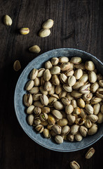 Roasted pistachios bowl. Backlith and wooden background