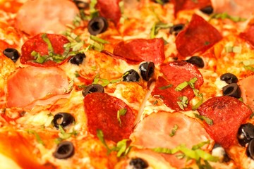 Homemade salami pizza with ham and olives. Close-up view of fresh pizza.