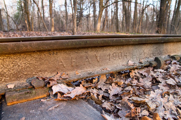 Industrial landscape - fragment of an old german single-track railway close-up, covered with dry oak leaves, on the sunset in Ukraine
